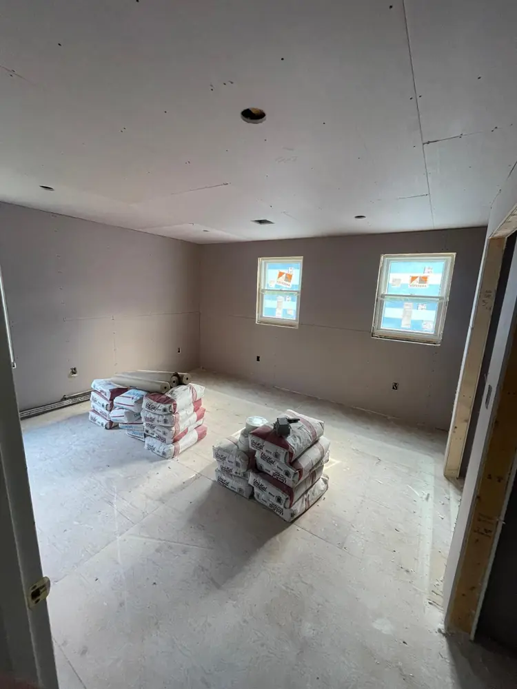 Bedroom with new drywall and compound bags ready for finishing